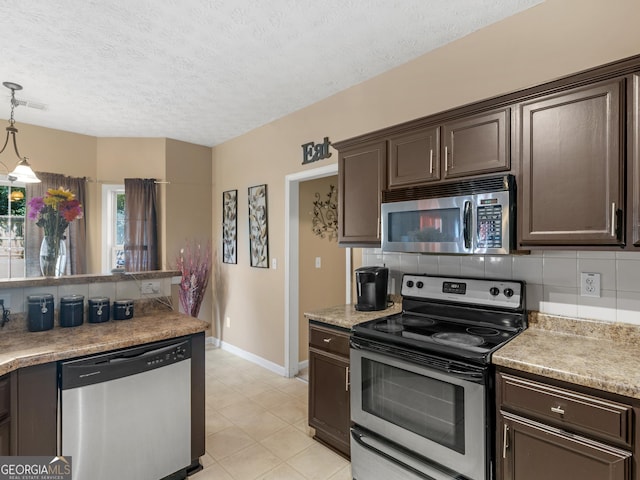 kitchen with appliances with stainless steel finishes, backsplash, dark brown cabinetry, a textured ceiling, and decorative light fixtures