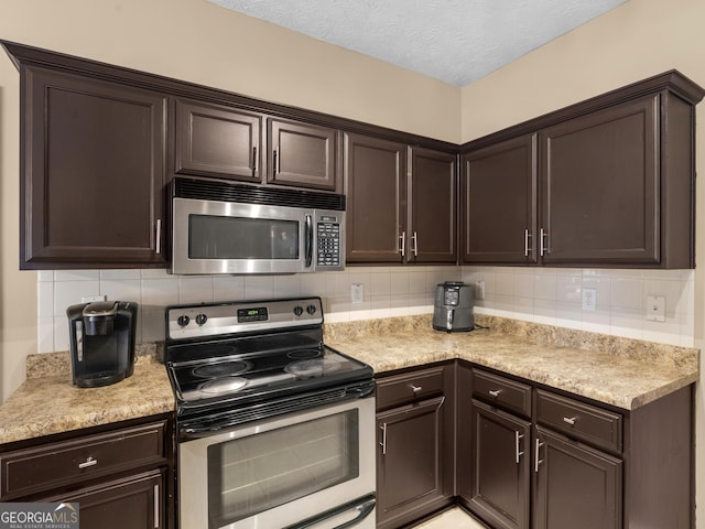 kitchen featuring backsplash, dark brown cabinetry, a textured ceiling, and appliances with stainless steel finishes