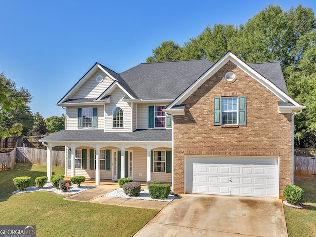 view of front of property with covered porch, a garage, and a front yard