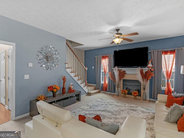 living room featuring a textured ceiling, ceiling fan, and light carpet