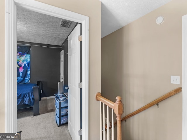 hallway with light carpet, a textured ceiling, and lofted ceiling