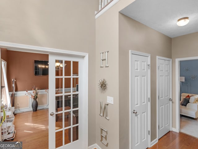 interior space with french doors, hardwood / wood-style floors, a towering ceiling, and a textured ceiling