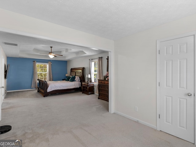 carpeted bedroom with a textured ceiling, a raised ceiling, and ceiling fan