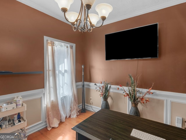 dining space featuring crown molding, light wood-type flooring, and a notable chandelier