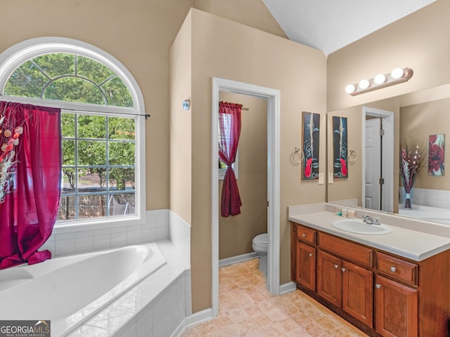 bathroom featuring vanity, a relaxing tiled tub, toilet, and lofted ceiling