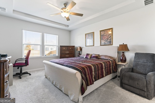 bedroom featuring ceiling fan, light carpet, and a tray ceiling