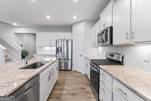 kitchen with wood-type flooring, sink, white cabinetry, and stainless steel appliances