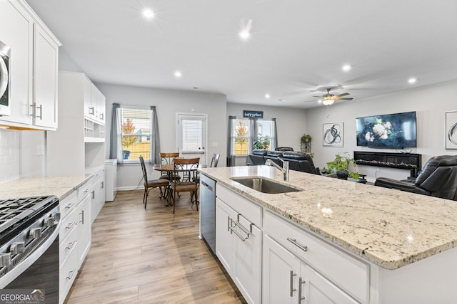 kitchen featuring appliances with stainless steel finishes, light wood-type flooring, white cabinetry, and a wealth of natural light