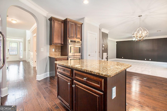 kitchen with a center island, stainless steel double oven, hanging light fixtures, light stone counters, and a chandelier