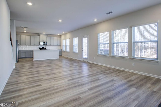 unfurnished living room featuring plenty of natural light and light wood-type flooring