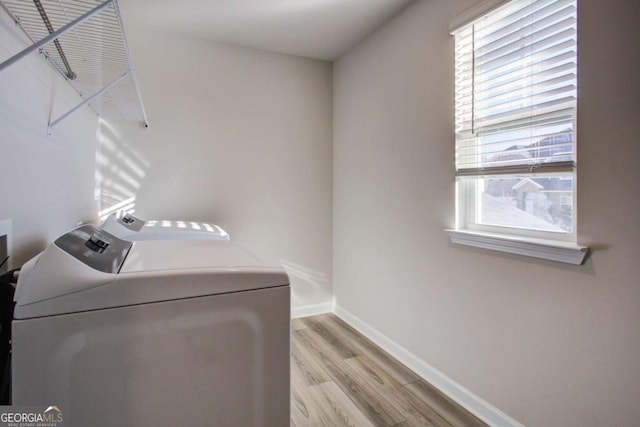 clothes washing area with separate washer and dryer, light hardwood / wood-style flooring, and a healthy amount of sunlight