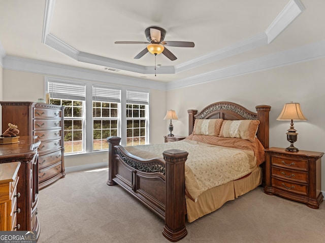 carpeted bedroom with a tray ceiling, ceiling fan, and crown molding