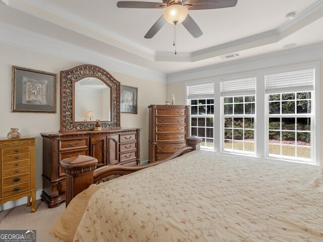 carpeted bedroom featuring ceiling fan, ornamental molding, and a tray ceiling