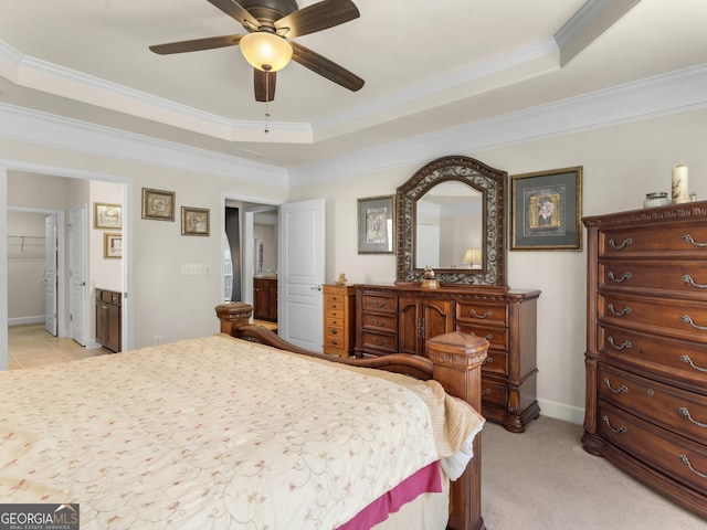 carpeted bedroom with ensuite bathroom, a raised ceiling, and crown molding