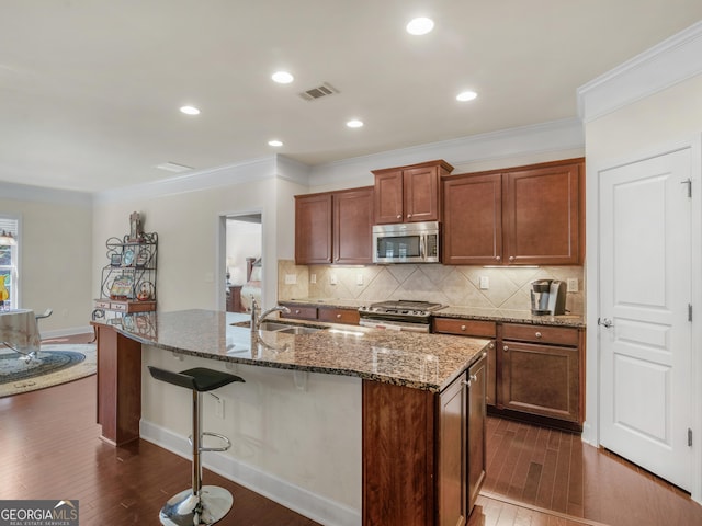 kitchen with appliances with stainless steel finishes, sink, dark hardwood / wood-style floors, and an island with sink