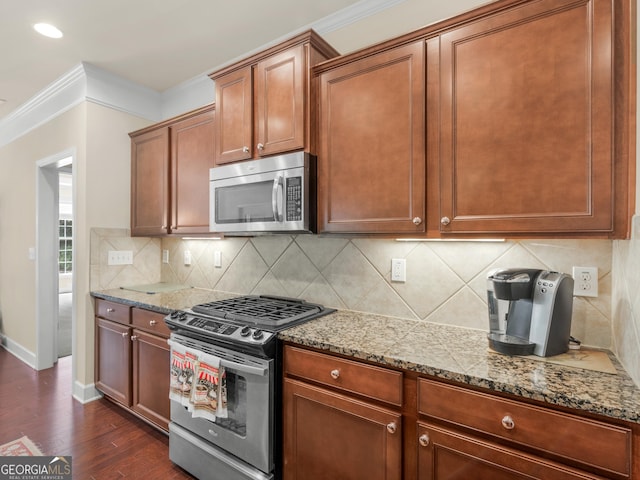 kitchen with dark wood-type flooring, stainless steel appliances, tasteful backsplash, light stone counters, and ornamental molding