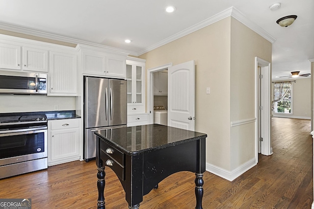 kitchen featuring white cabinets, appliances with stainless steel finishes, a center island, and dark stone countertops