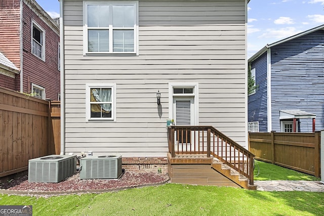 back of house featuring a lawn and central AC unit