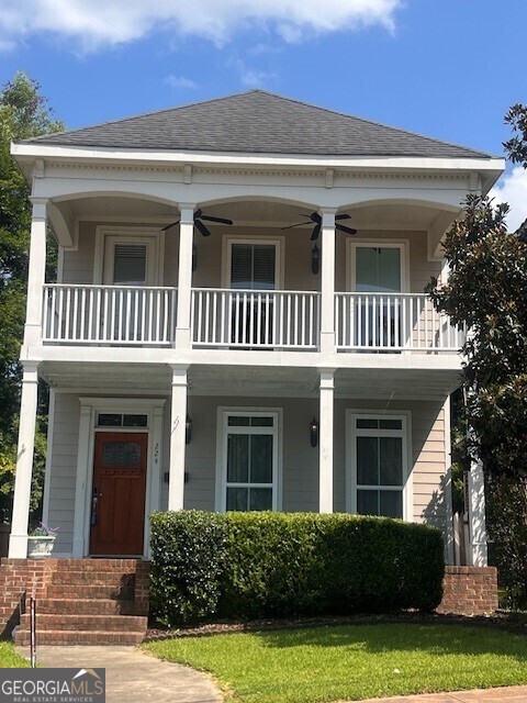 view of front of property featuring ceiling fan, a balcony, and a front yard