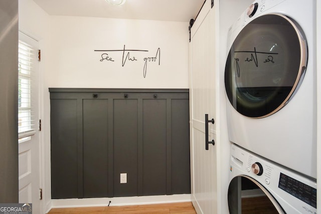 laundry room with a barn door and stacked washing maching and dryer