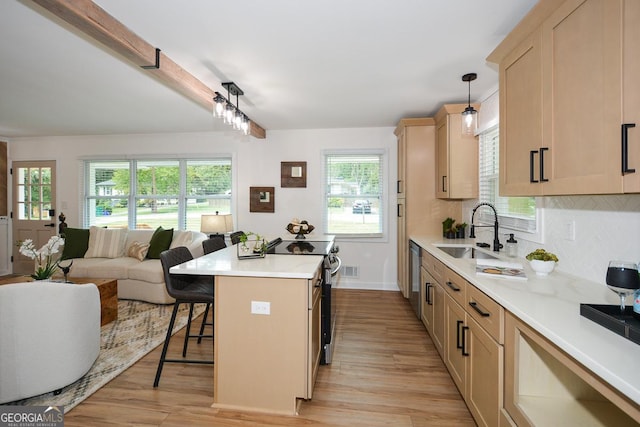 kitchen with pendant lighting, a breakfast bar, sink, appliances with stainless steel finishes, and a kitchen island