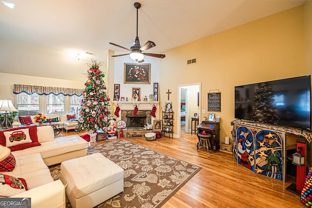 living room featuring a fireplace, hardwood / wood-style floors, vaulted ceiling, and ceiling fan