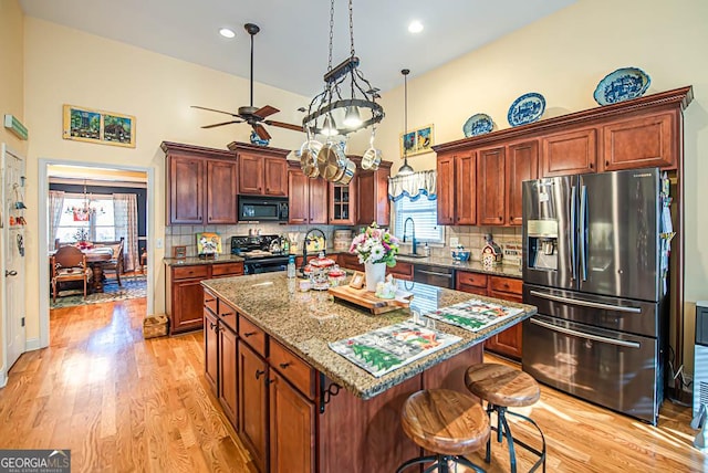 kitchen featuring black appliances, plenty of natural light, a kitchen island, and backsplash