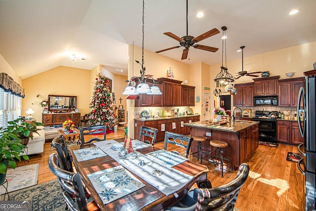 dining room with light wood-type flooring, ceiling fan, lofted ceiling, and sink