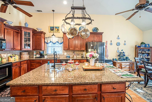 kitchen with black appliances, a kitchen island with sink, and tasteful backsplash