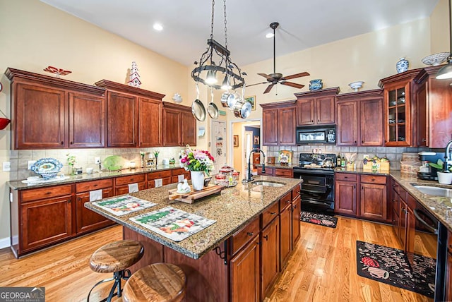 kitchen featuring black appliances, a kitchen breakfast bar, sink, an island with sink, and tasteful backsplash