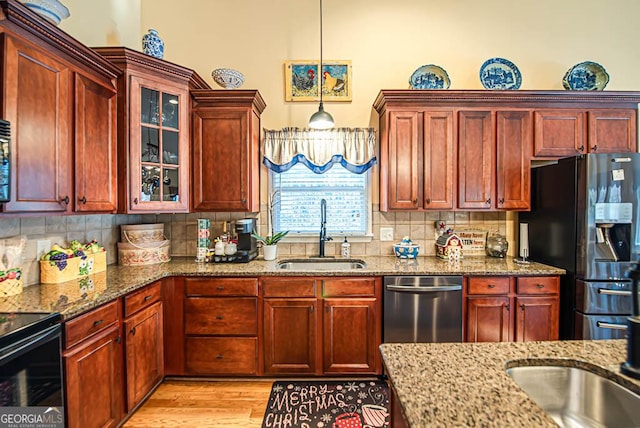 kitchen featuring light stone countertops, sink, stainless steel appliances, backsplash, and pendant lighting