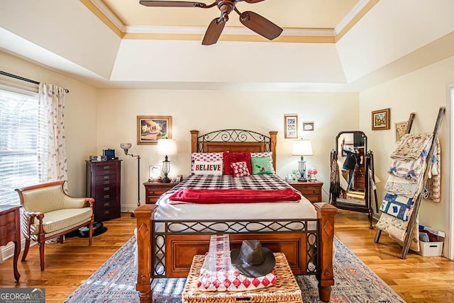 bedroom featuring ceiling fan, light hardwood / wood-style flooring, and a tray ceiling