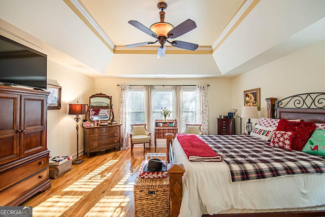 bedroom featuring light hardwood / wood-style floors, a raised ceiling, ceiling fan, and ornamental molding