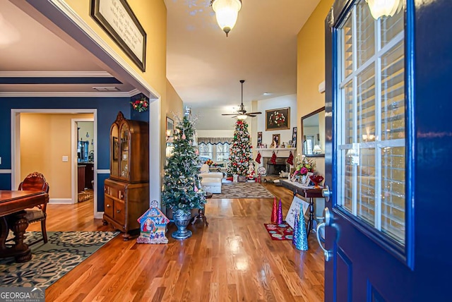 entryway featuring ceiling fan, crown molding, and light wood-type flooring