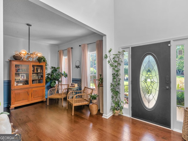 entrance foyer featuring a textured ceiling, dark hardwood / wood-style floors, crown molding, and a notable chandelier