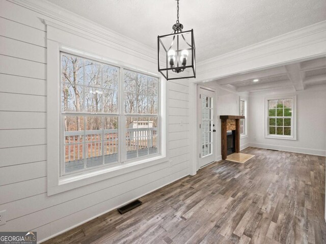 unfurnished living room featuring crown molding, wood walls, hardwood / wood-style floors, and a chandelier