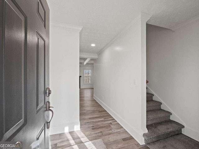 foyer with beam ceiling, light hardwood / wood-style floors, ornamental molding, and coffered ceiling