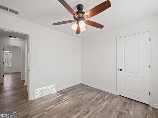 empty room with hardwood / wood-style floors, ceiling fan, and a textured ceiling