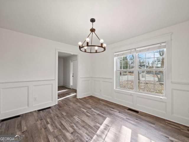 unfurnished dining area featuring a chandelier and hardwood / wood-style floors