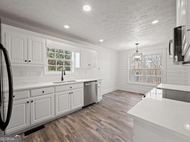 kitchen with white cabinetry, sink, wooden walls, and appliances with stainless steel finishes