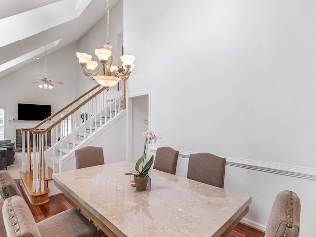 dining room featuring hardwood / wood-style floors, ceiling fan with notable chandelier, and high vaulted ceiling