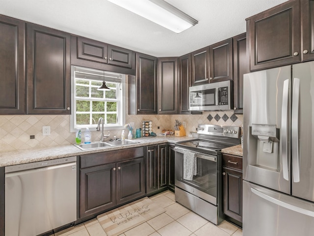 kitchen featuring light tile patterned floors, dark brown cabinetry, stainless steel appliances, and sink