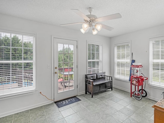 doorway to outside with light tile patterned floors, a textured ceiling, and ceiling fan