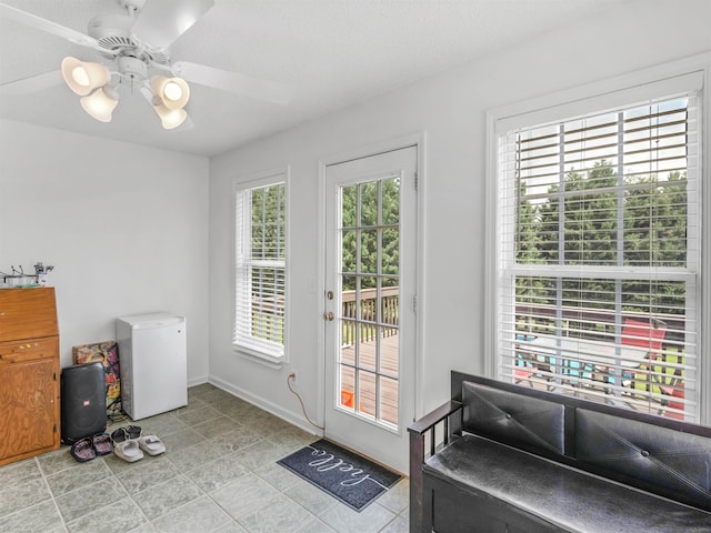 doorway with ceiling fan, plenty of natural light, and a textured ceiling