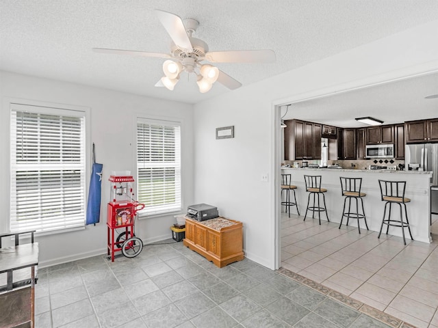 interior space featuring a textured ceiling, ceiling fan, and light tile patterned flooring