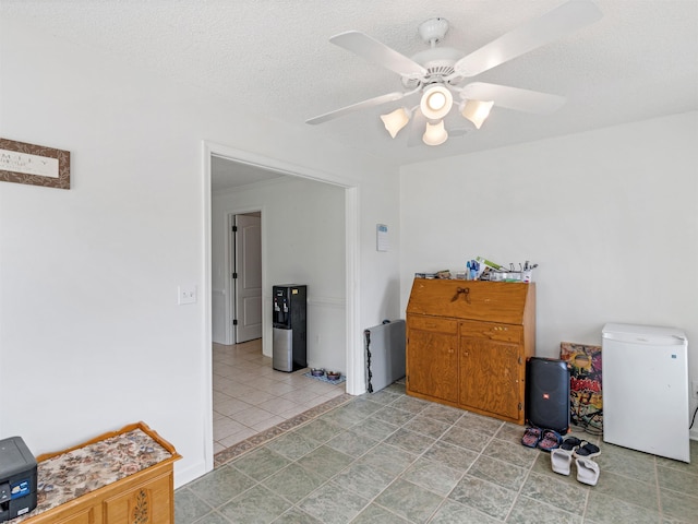 interior space with a textured ceiling and ceiling fan