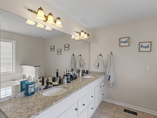 bathroom with tile patterned flooring, a textured ceiling, vanity, and a bathing tub