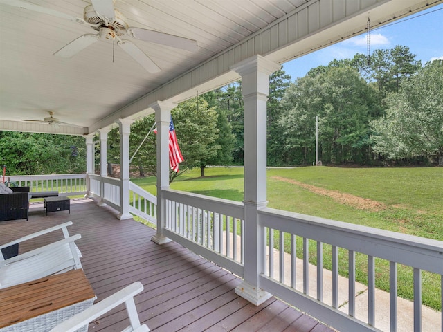 wooden terrace featuring a porch, ceiling fan, and a lawn