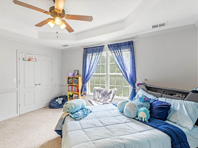 bedroom featuring carpet, crown molding, ceiling fan, a tray ceiling, and a closet