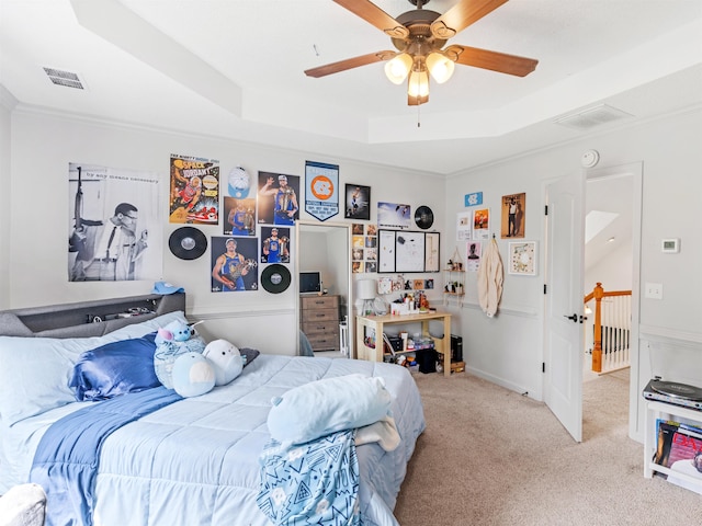 bedroom with a tray ceiling, ceiling fan, light carpet, and ornamental molding